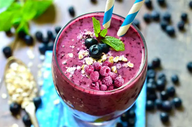 Top view of fruity smoothie with berry toppings.