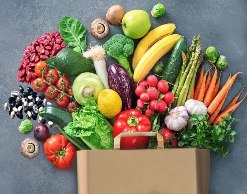 Tons of healthy fruits & vegetables spilling out of a bag display foods high in fiber.