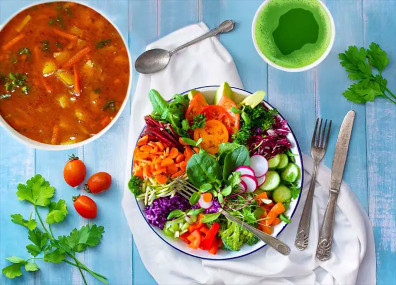 Loaded bowls of soup and salad on a bright board.