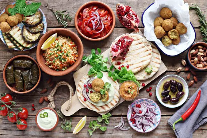 An array of vegan wrap ingredients including tortillas, veggies, and falafel. 