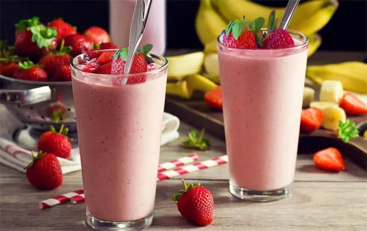 Two delicious strawberry banana smoothies topped with fresh strawberries.