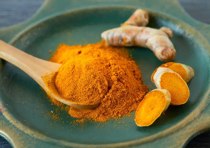 Plate of turmeric powder and sliced root. 