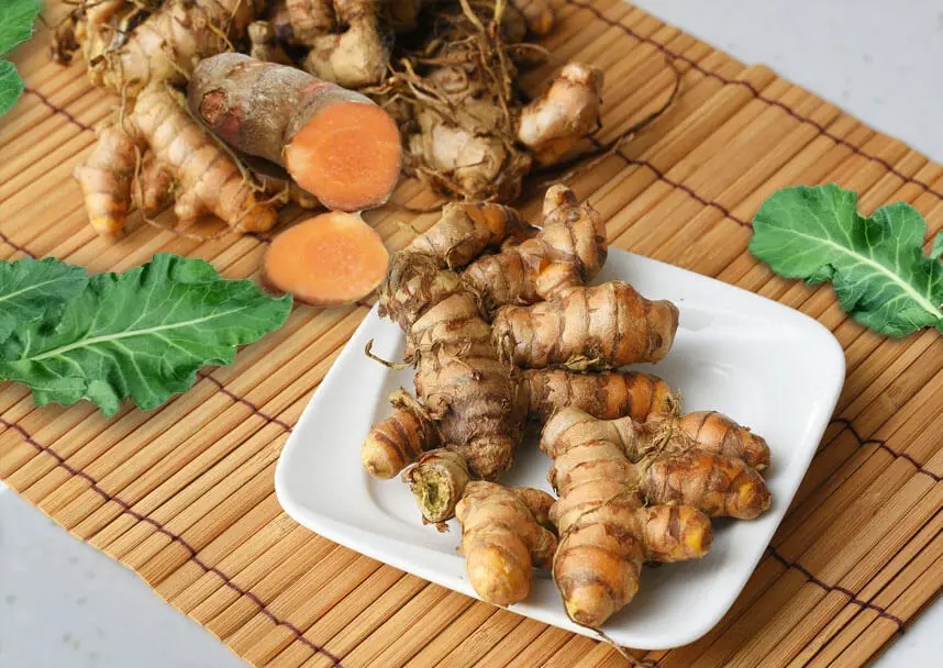 Bunches of turmeric root displayed on a bamboo mat. 