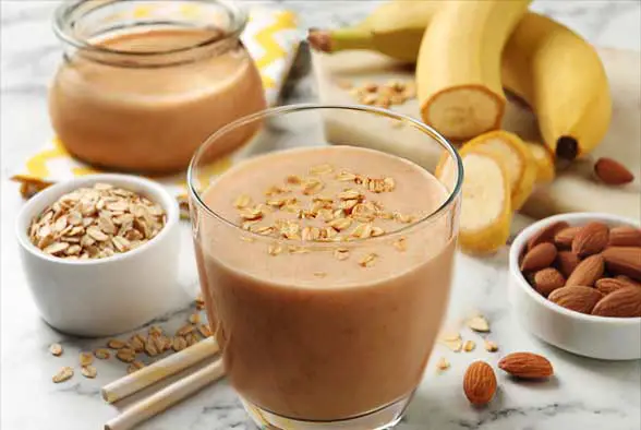 Two almond butter smoothies with fresh almonds and banana.