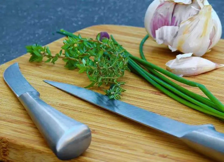 Raw garlic and chives on a cutting board. 