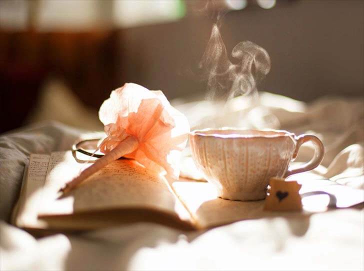 A cup of steamy tea on an open notebook. 