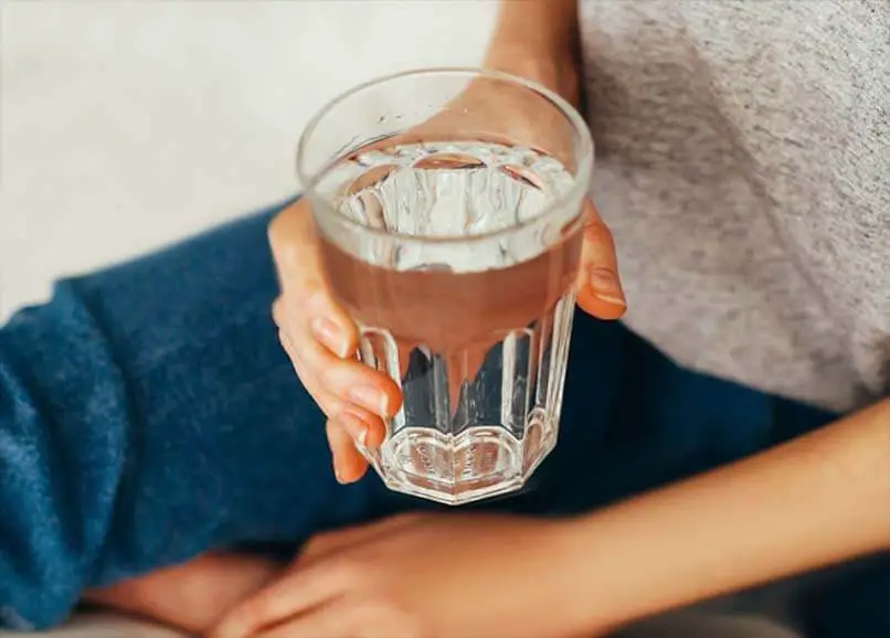 A girl holding a full glass of water. 