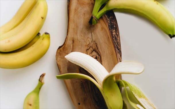 Peeled and unpeeled bananas on a wooden board. 