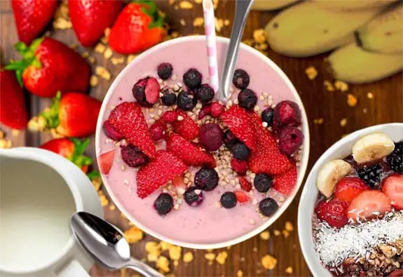 Top view of stacked strawberry banana smoothie, fresh fruit, and plant milk.