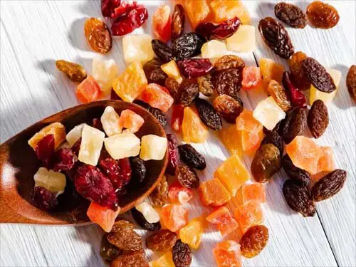 Spoonful of colorful mixed dried fruit squares spread across a board.   