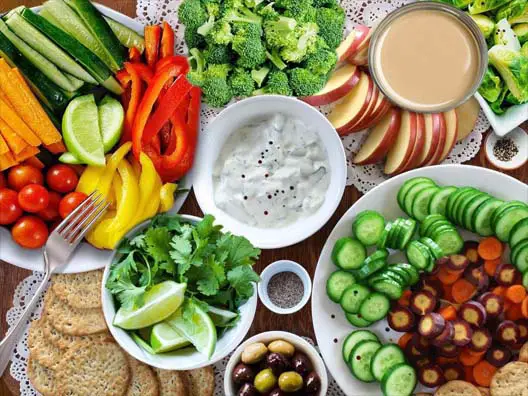 Top view of appetizers, finger foods, and an array of succulent dips on a decorative tabletop.