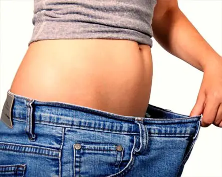 Girl in baggy pants displays her shrunken waistline. 