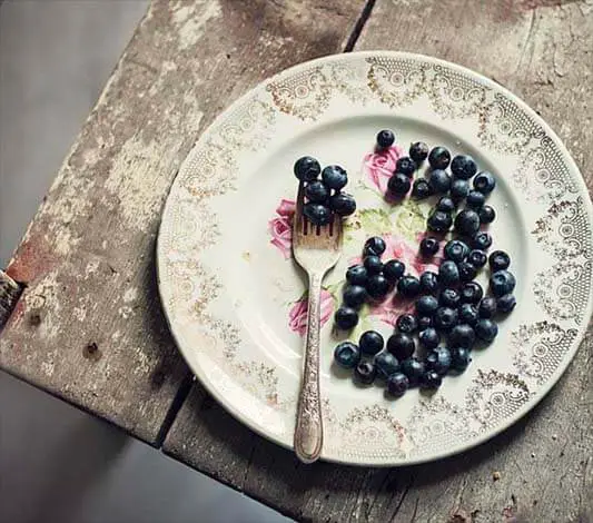 Top view of a plate of blueberries on a rustic table. 