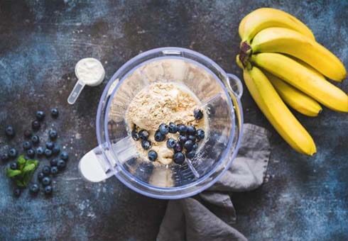 Top view of a stacked blender with blueberries and vegan protein powder. 