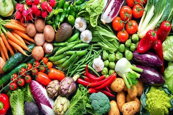 Tons of colorful raw fruits and veggies packed on a board.  
