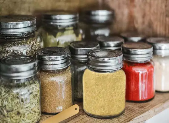 Rows of mason jars in a pantry display nutritional yeast and scores of herbs. 