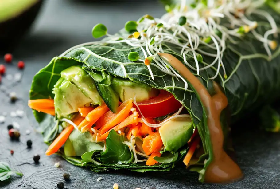 Close-up of a scrumptious lettuce wrap topped with sprouts and packed with tofu, veggies, avocado, and a creamy rich peanut sauce. 