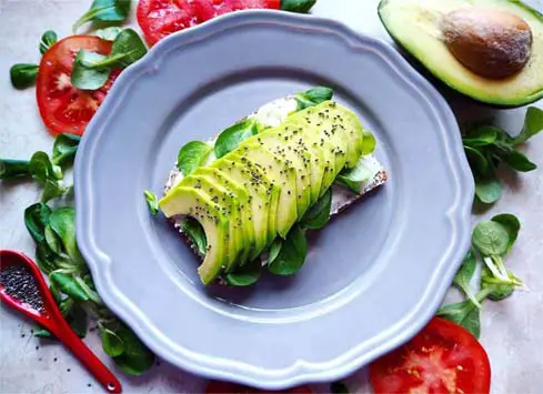 Top view of avocado toast and greens. 