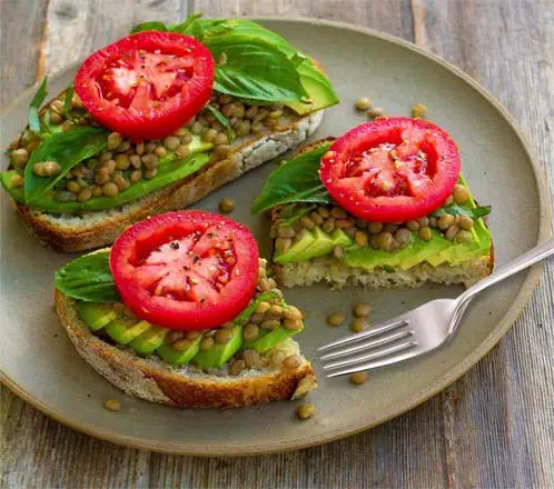 Avocado toast, tomatoes, and lentils on a plate. 