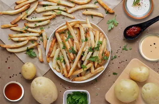 Top view of homemade French fries with dips, herbs, fresh potatoes. 