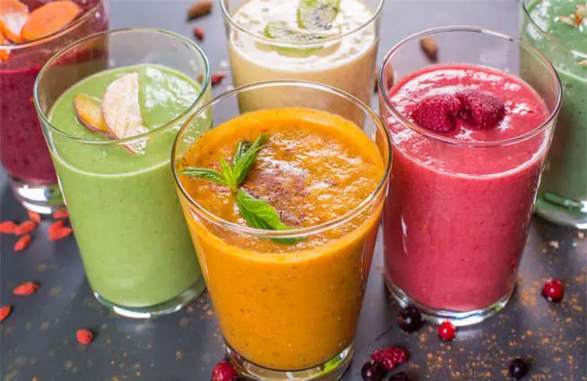 An array of rich colorful fruity smoothies in tall glasses. 