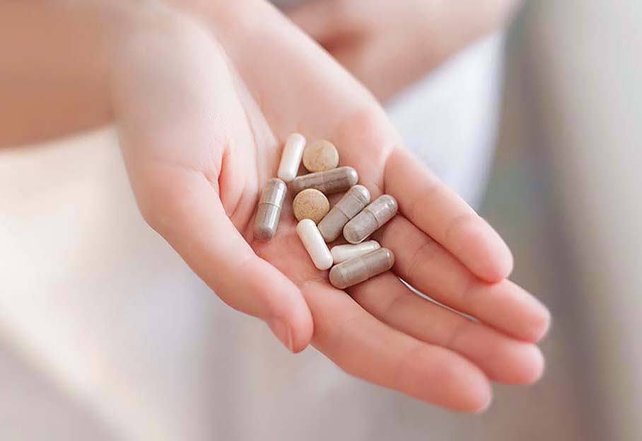 Close-up of a girl's palm holding an assortment of supplements. 