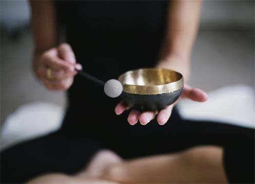 Girl in meditation posture with a singing bowl.  