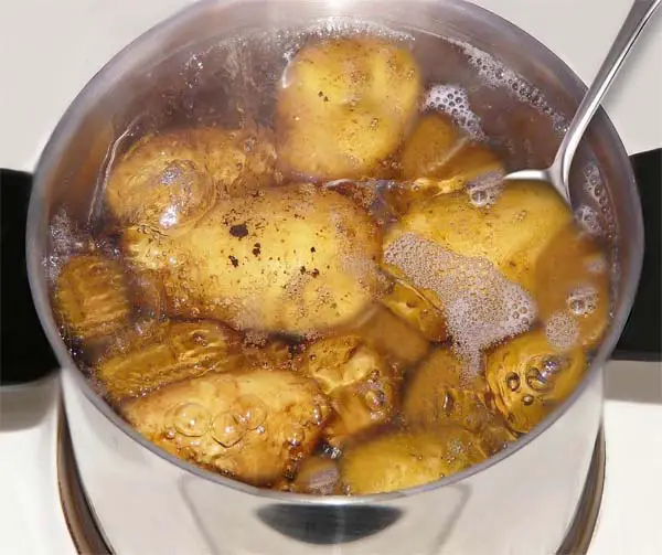 Top view of boiling whole potatoes in a pot. 