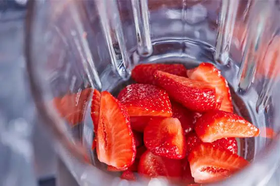 Top view of juicy fresh organic strawberries stacked in a blender for a smoothie. 