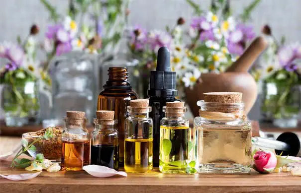 An array of essential oils against a backdrop of wildflowers. 