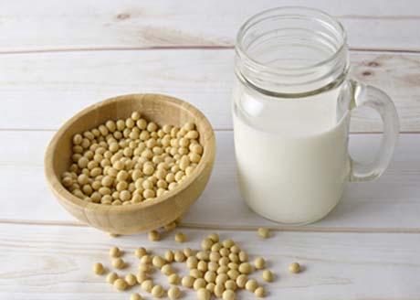 Bowl of soybeans beside a mug of soymilk. 