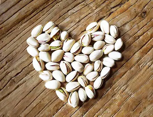 Heart-shaped pistachios on a board. 