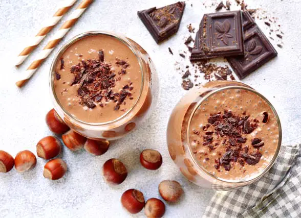 Top view of two delicious vegan chocolate milkshakes with cacao nibs, chocolate chunks, and hazelnuts.  