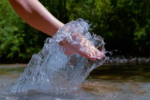 Close-up of a woman's foot dipping into a cold stream.