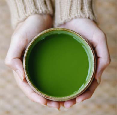 Close on a girl's hands holding a mug of rich green tea. 