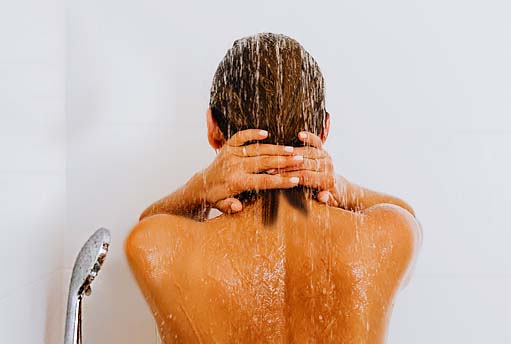 A girl clasping the back of her neck in a cold shower. 