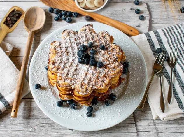 Top view of Himalayan Tartary Buckwheat waffles with blueberries, bananas, and cacao nibs on a wooden board.   