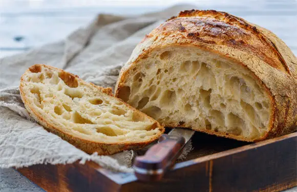 Sliced loaf of crusty Himalayan Tartary Buckwheat sourdough bread on a cutting board.