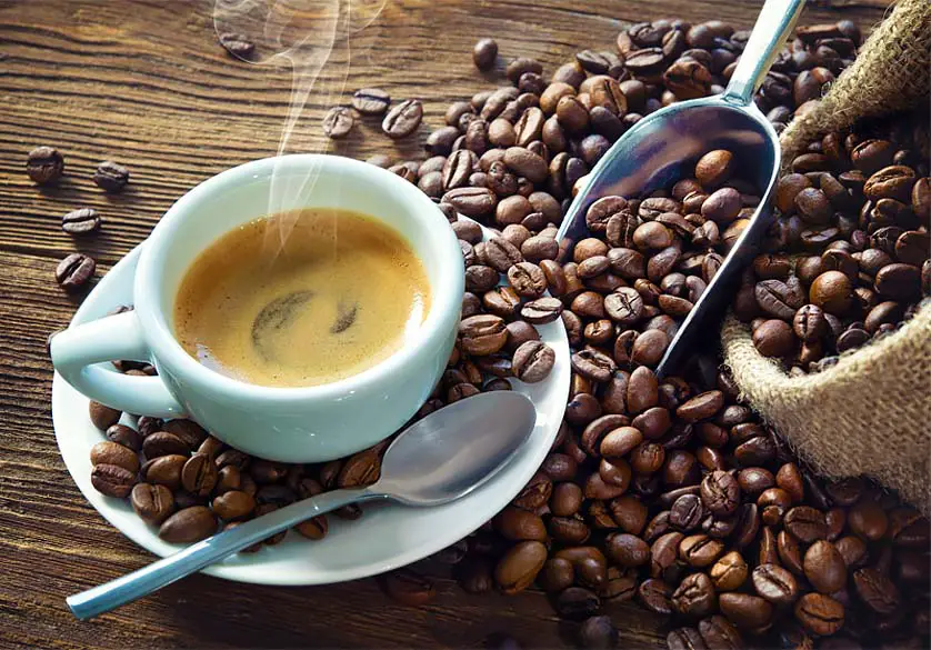 Mug of steamy hot infrared coffee surrounded by rich infrared coffee beans.