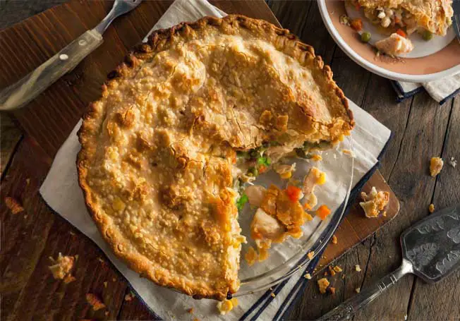 Top view of rich vegan chicken pot pie with Himalayan Tartary Buckwheat crust sliced open atop a rustic board and kitchen cloth.