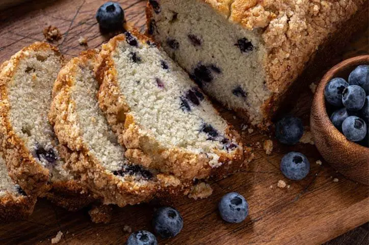 Close-up of Himalayan Tartary Buckwheat blueberry bread slices and fresh berries on a cutting board.