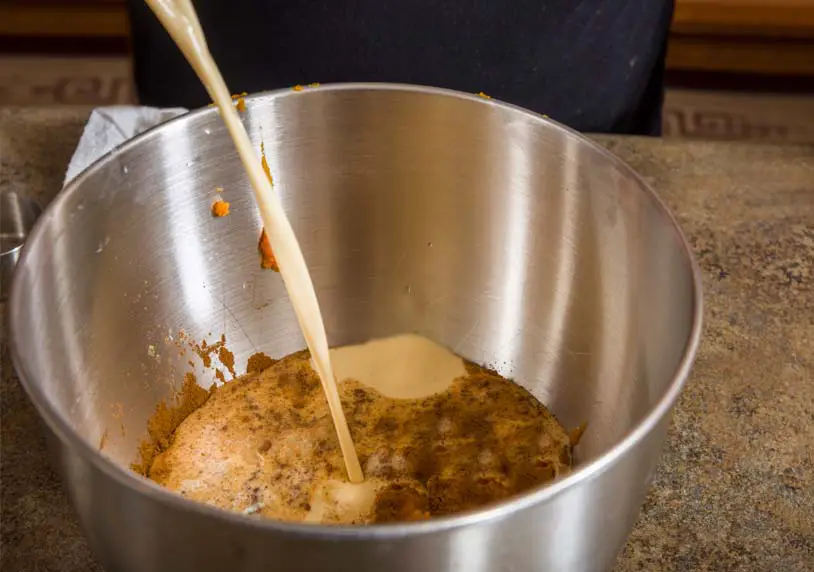 A stainless mixing bowl of ingredients for this pumpkin pie recipe's filling. 