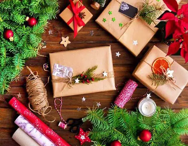 Top view of assorted gifts and colorful wraps, wreaths, and poinsettia in a decorative holiday display.