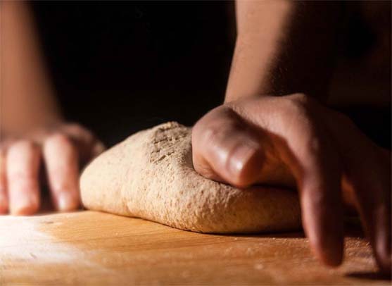 A woman's hands kneading a rich mound of Himalayan Tartary Buckwheat calzone dough.