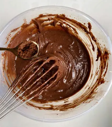 Top view vegan buckwheat brownie batter and utensils in a glass mixing bowl. 