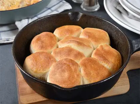 Golden freshly baked biscuits in a cast iron pan on a tabletop. 