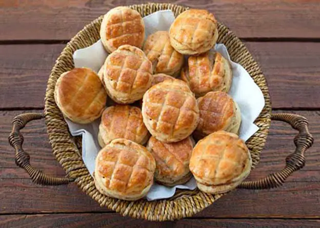 Top view of rich vegan buckwheat biscuits in a wicker basket on a rustic board.