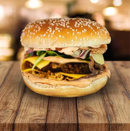 Close-up of vegan Volcano Burger with sesame buns and cheese on a wooden plank.