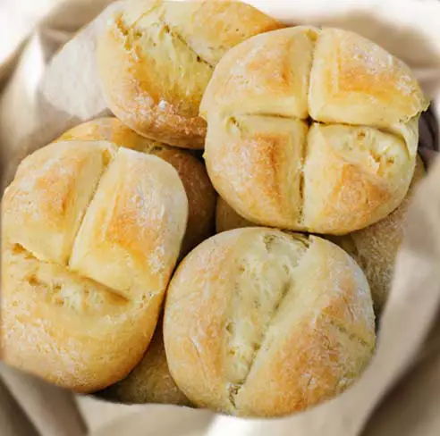 Close-up of mouthwateringly delicious sourdough dinner rolls in a cloth-lined basket.