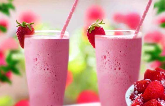 Two large succulent strawberry smoothies in tall glasses with fresh strawberry garnish and pink straws.